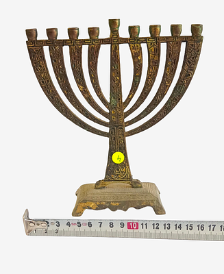 חנוכייה פליז עתיקה סרט מדידה להמחשת הגודל. חנוכייה פליז עתיקה על רקע ניטרלי . פריט יודאיקה