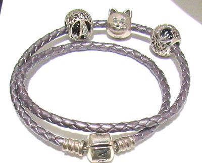PANDORA STERLING SILVER & BRAIDED LEATHER BRACELET. 3 CHARMS.