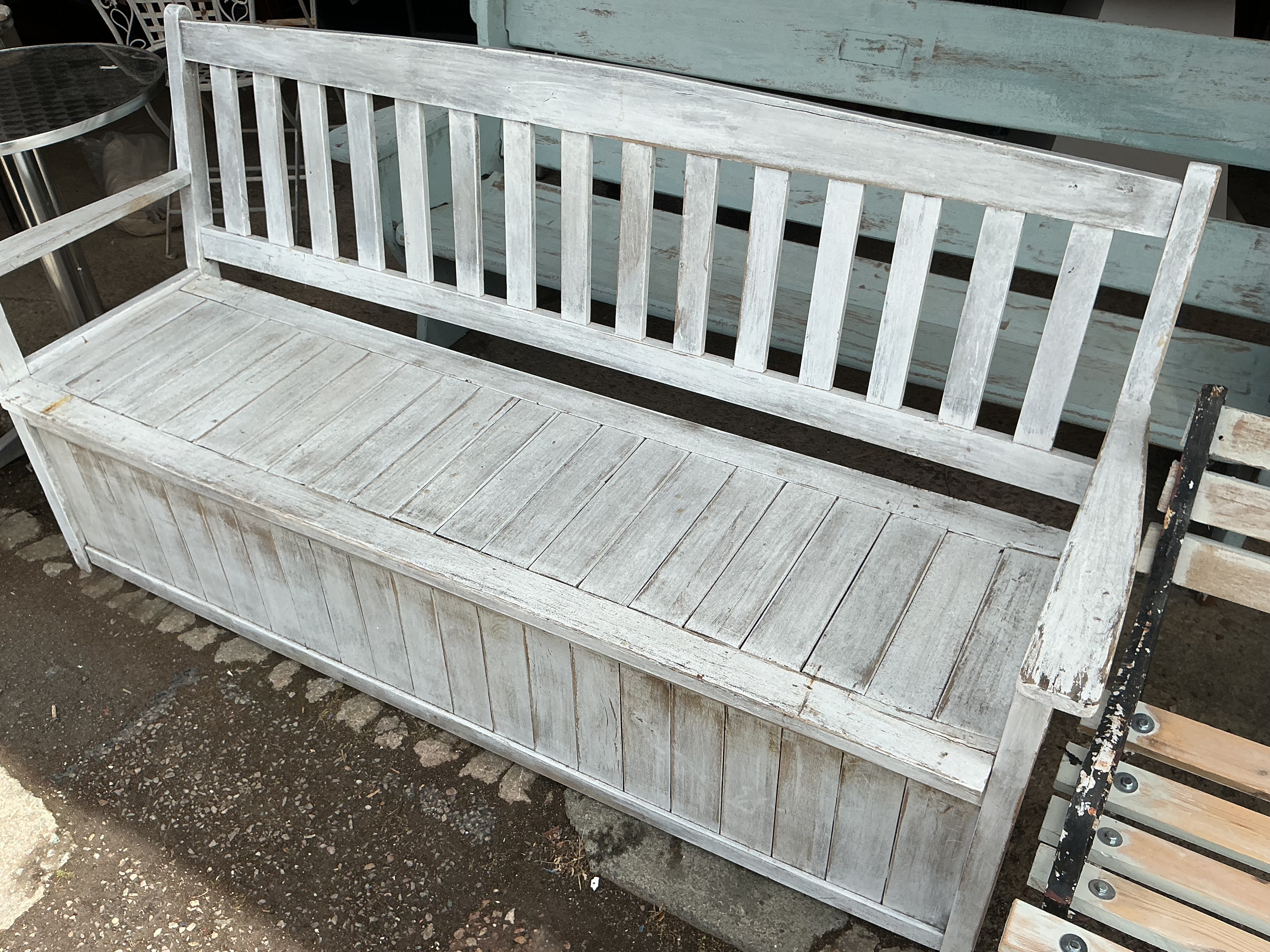 A rustic white painted wood storage garden bench