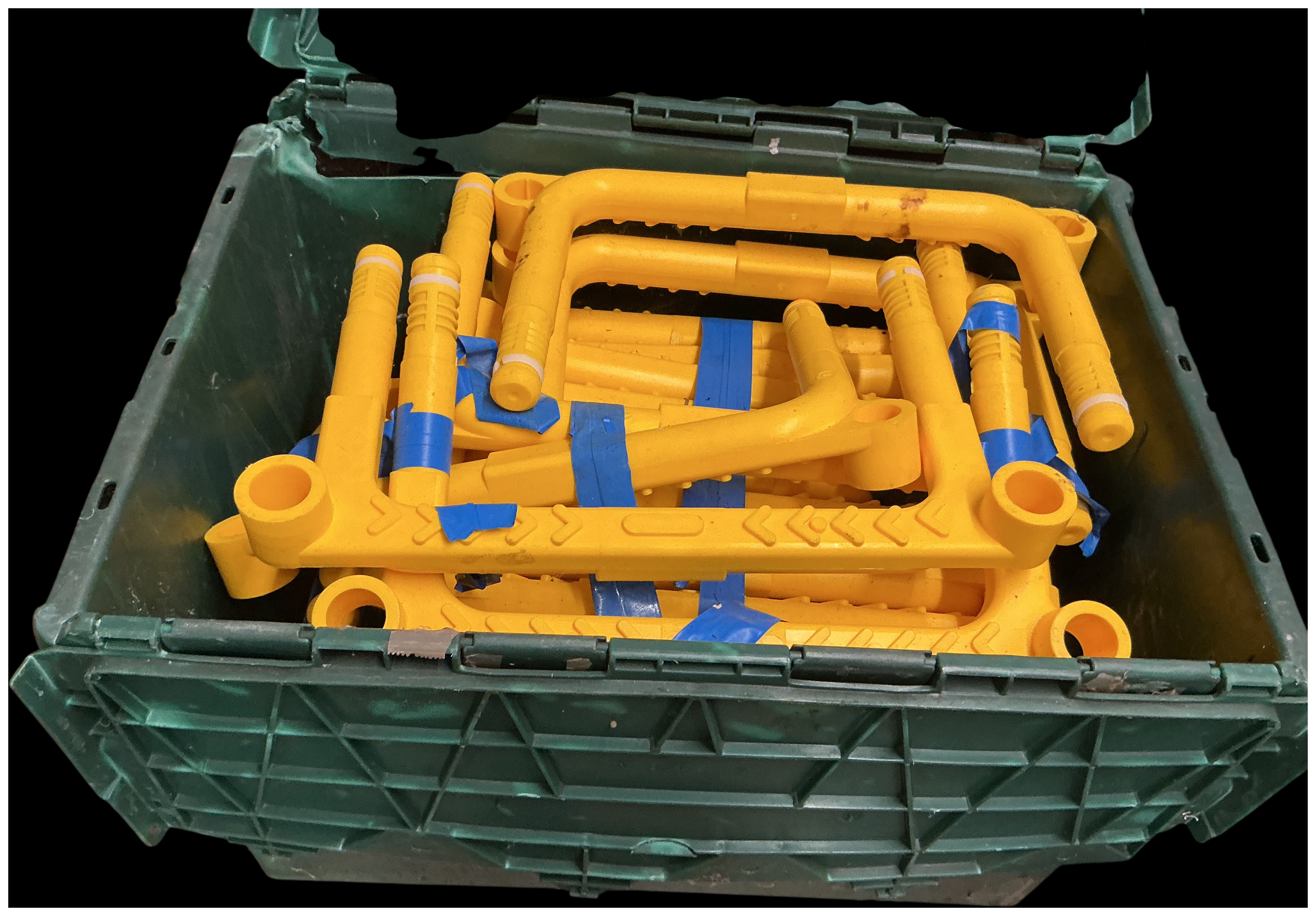 An Assortment of Yellow Moulded Plastic Industrial Safety Barrier Components in a Green Pallet Crate