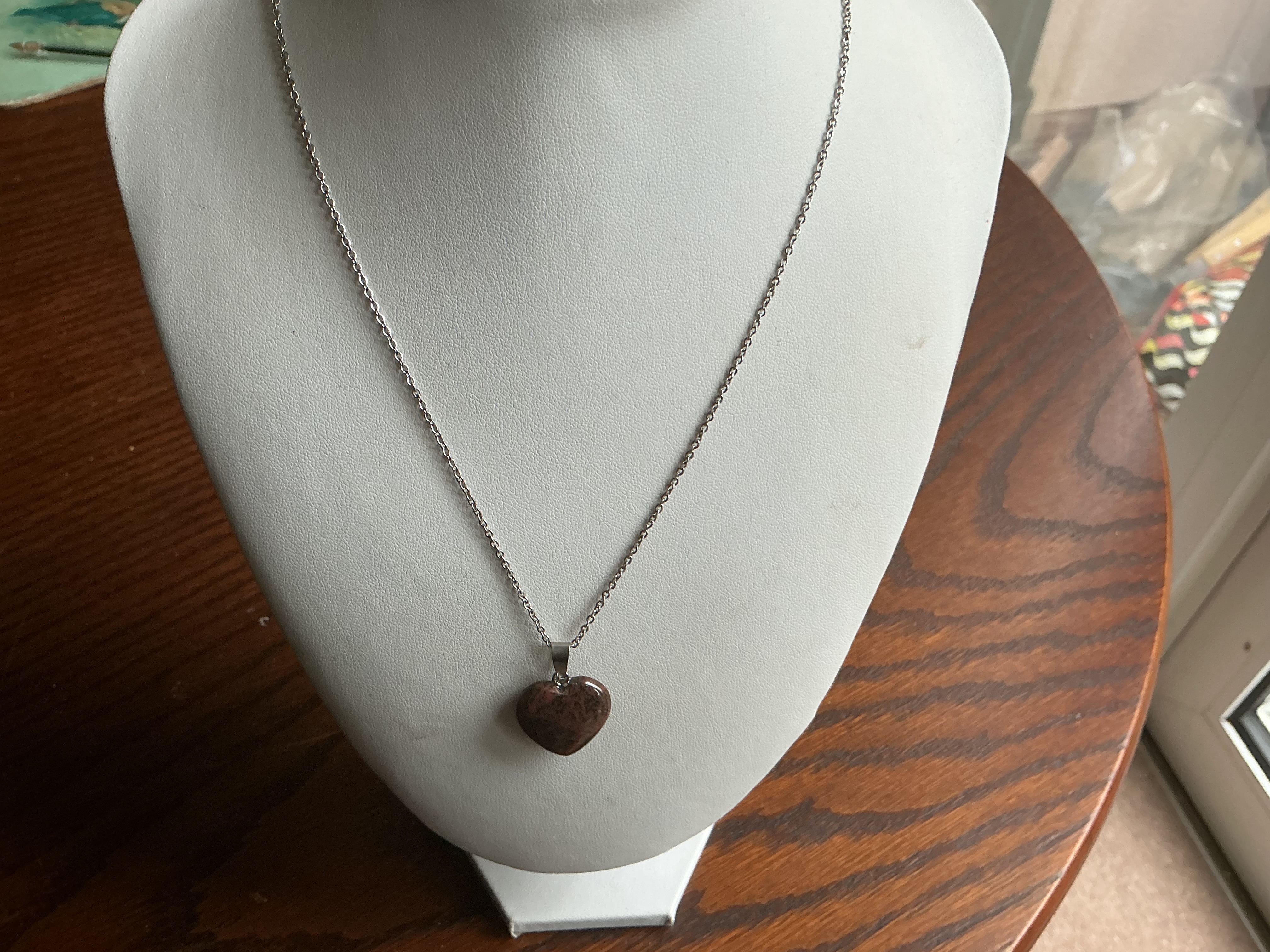 January. A mahogany obsidian heart-shaped pendant on a silver-toned trace link chain