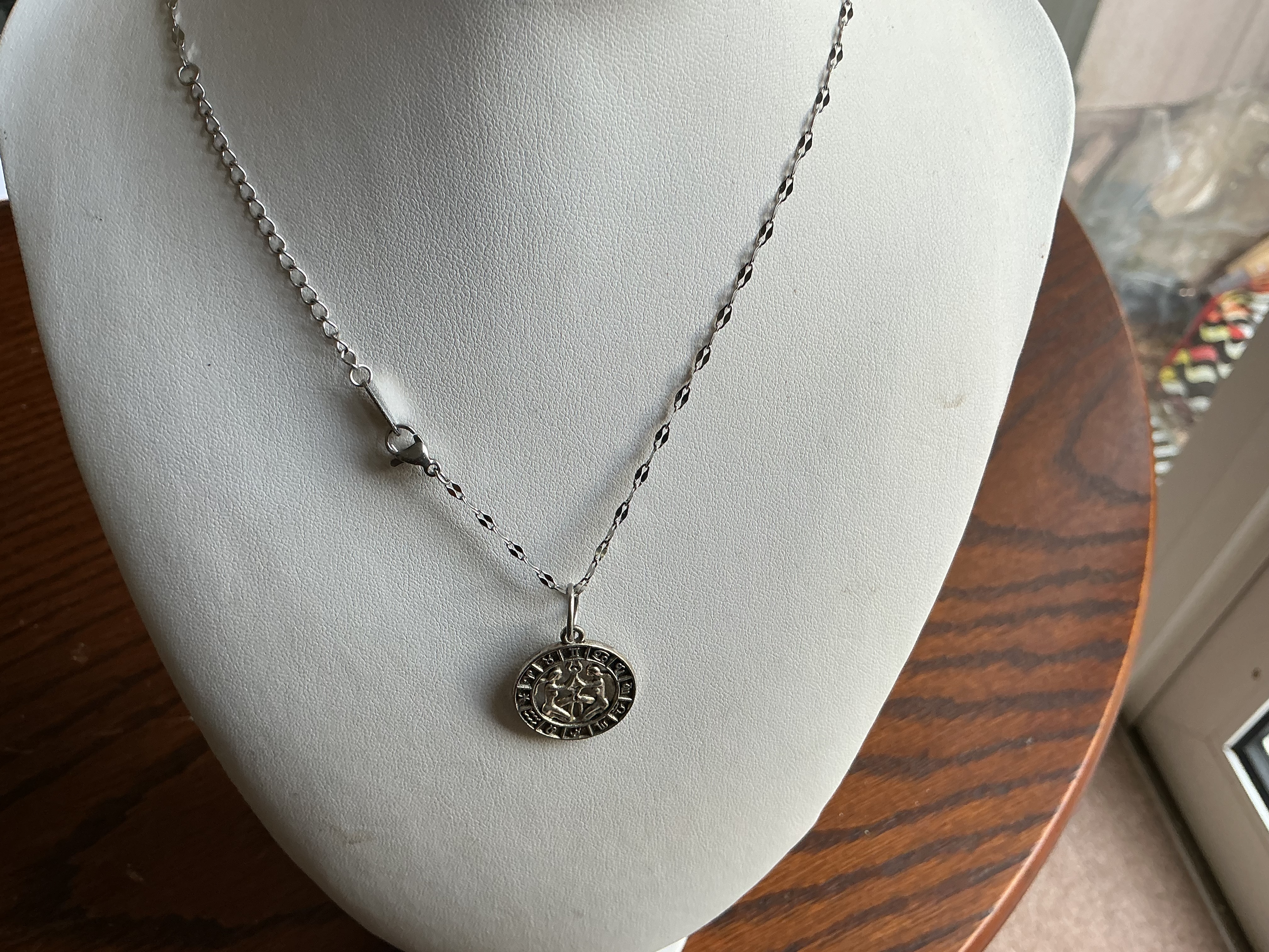 A Gemini zodiac medallion pendant necklace in silver-toned metal