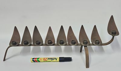 חנוכית פליז בעיצובו של האומן לודוויג יהודה וולפרט (1900-1981), חתומה על רגל החנוכיה , אורך 