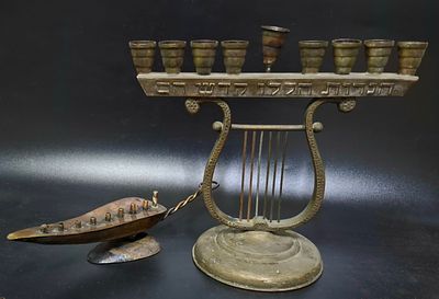 זוג חנוכיות ישראליות ישנות מנחושת. אחת בצורת אלדין רוחב 24 ס"מ השניה בצורת נבל כיתוב בחזית 