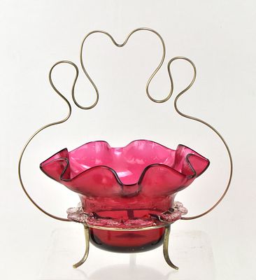 CRANBERRY GLASS BOWL WITH A SILVER BASKET. A hand-blown cranberry glass bowl with ruffled rims 