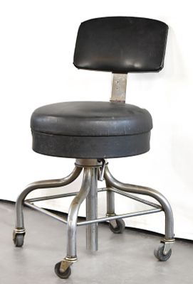 INDUSTRIAL MEDICAL STOOL. Industrial black vinyl and metal medical stool on castors. Measures 