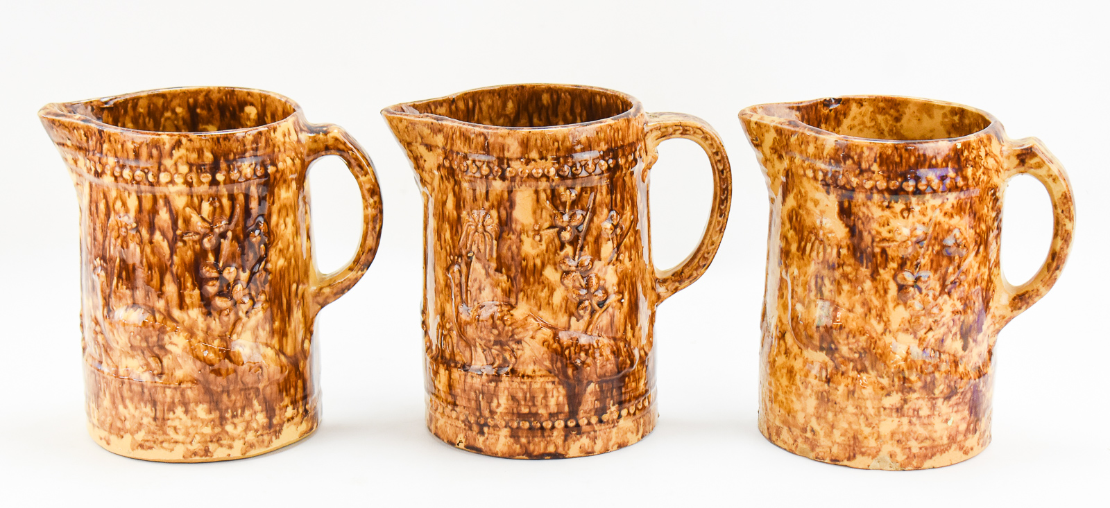 THREE AMERICAN 'PEACOCK AND PALM TREE' ROCKINGHAM STYLE PITCHERS