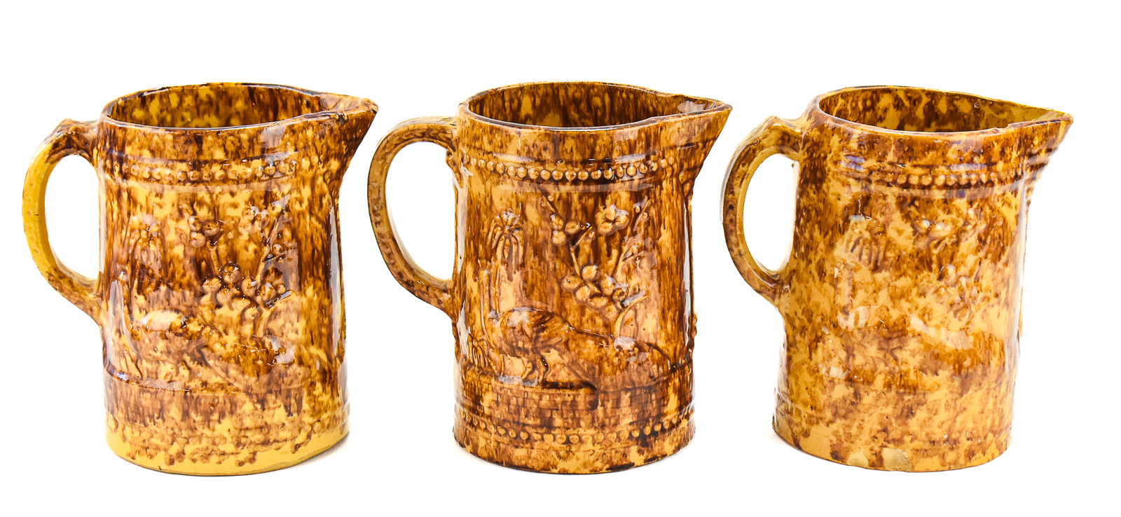 THREE AMERICAN 'PEACOCK AND PALM TREE' ROCKINGHAM STYLE PITCHERS
