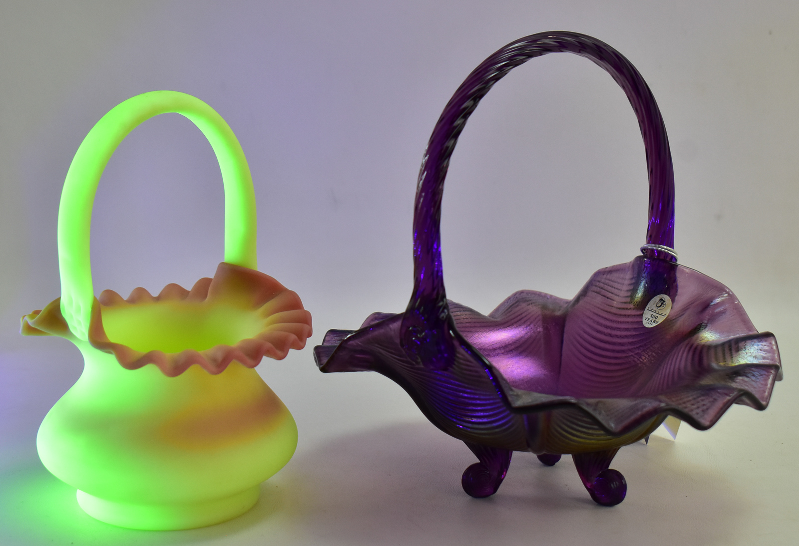 PAIR OF FENTON ART GLASS BASKETS: AMETHYST CARNIVAL GLASS AND BURMESE GLASS