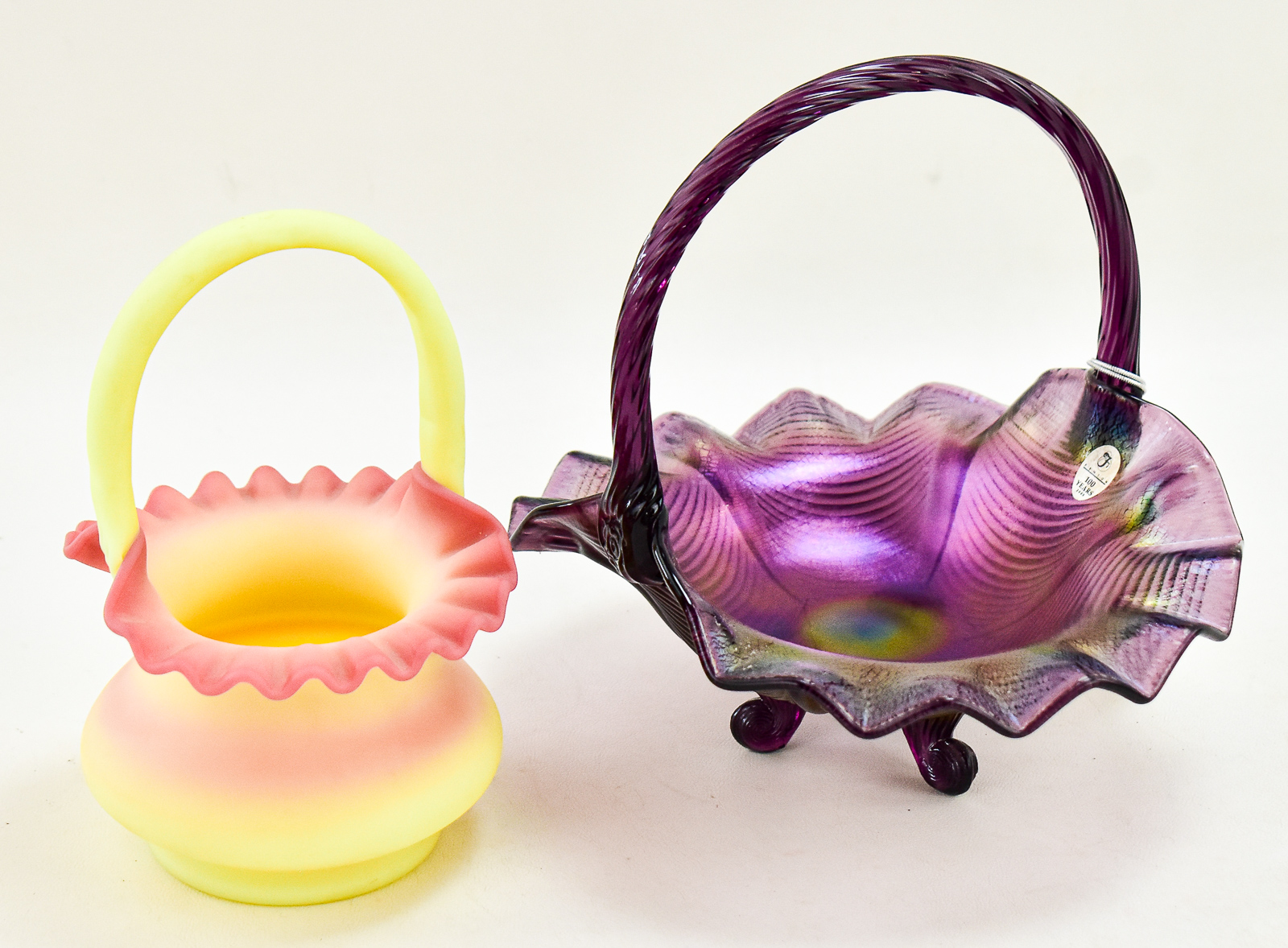 PAIR OF FENTON ART GLASS BASKETS: AMETHYST CARNIVAL GLASS AND BURMESE GLASS