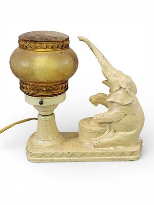 FIGURAL ELEPHANT LAMP. Early 20th century, spelter. With cream paint and an amber shade. 10.5" 