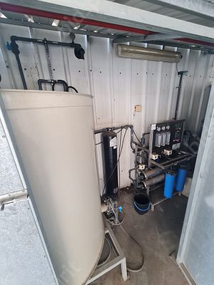 מערכת אוסמוזה הפוכה (RO) תעשייתית, הכוללת מיכל אגירה אנכי, יחידת בקרה עם מדי לחץ וספיקה