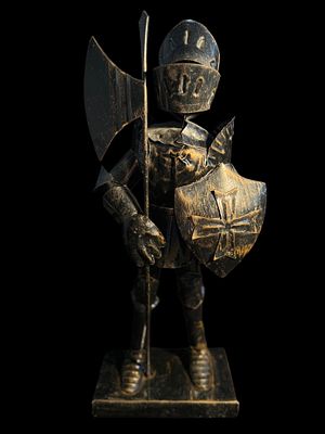 Cavaliere medievale in metallo. Scultura medievale, armatura dettagliata, scudo croce e ascia