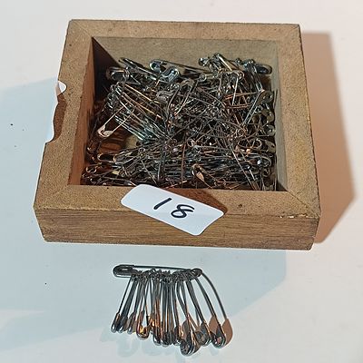 A Collection of Silver-Toned Metal Safety Pins in a Wooden Box