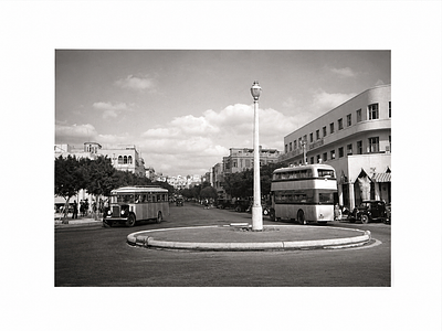צילום היסטורי של תל אביב – כיכר עירונית ואוטובוסים. הדפס צילום שחור־לבן המציג רחוב מרכזי בתל 
