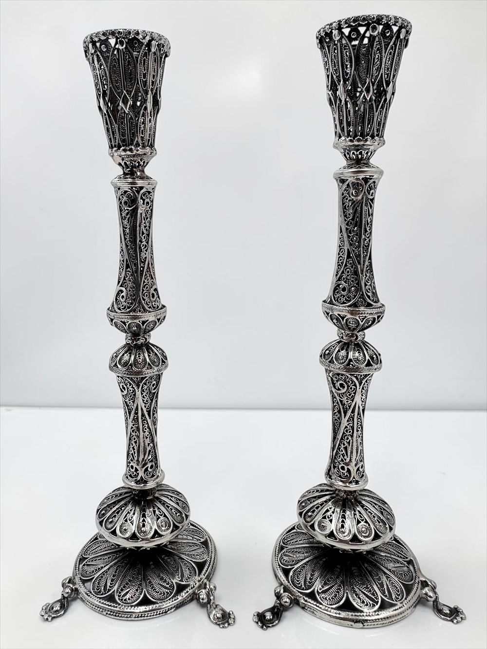 Shoham Simchi silversmith, filigree-rich candlestick holders. Each candle holder stands on 