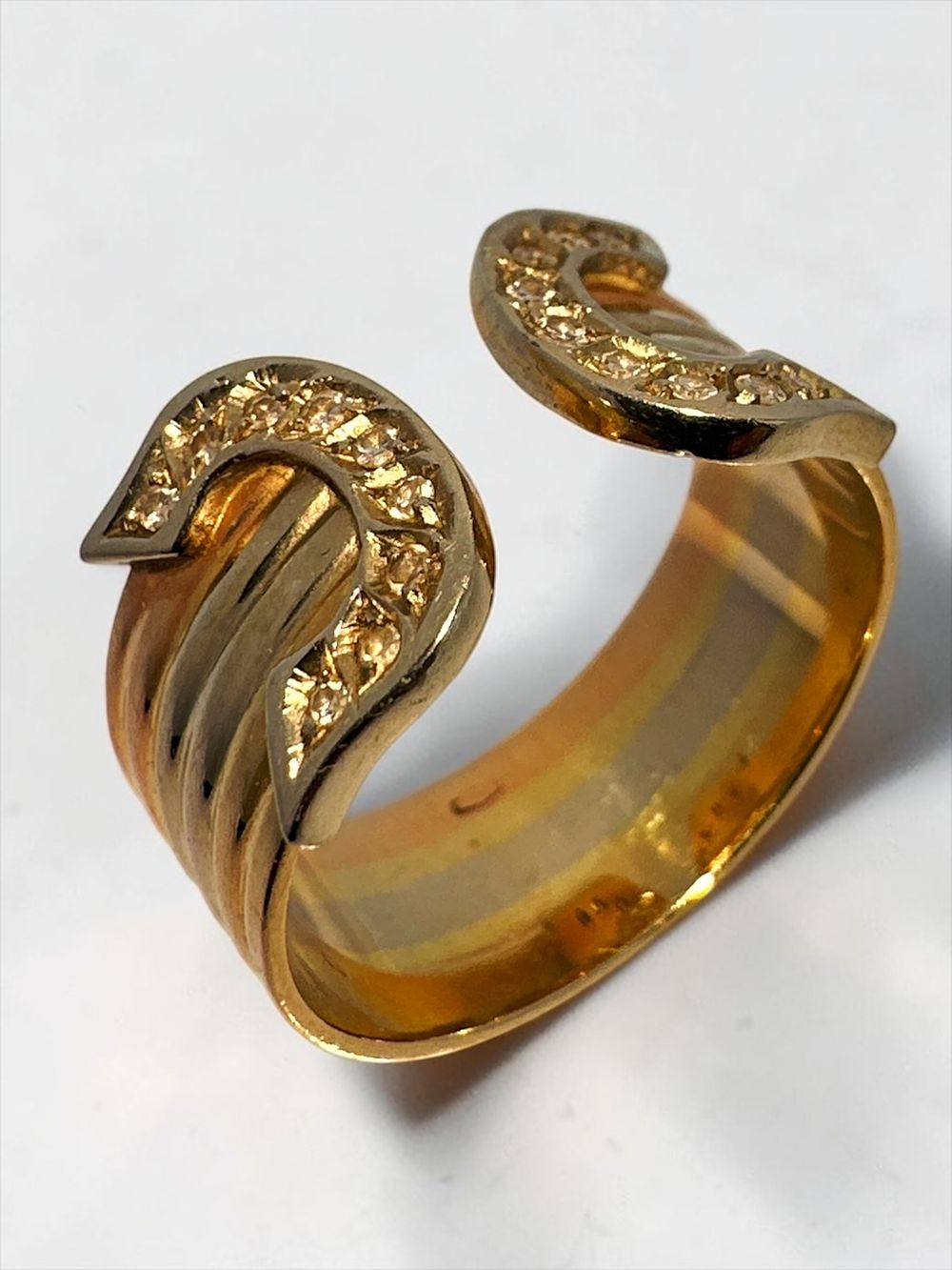 18k gold ring in an open ended horse shoe like design. In yellow, rose and white gold. Set 