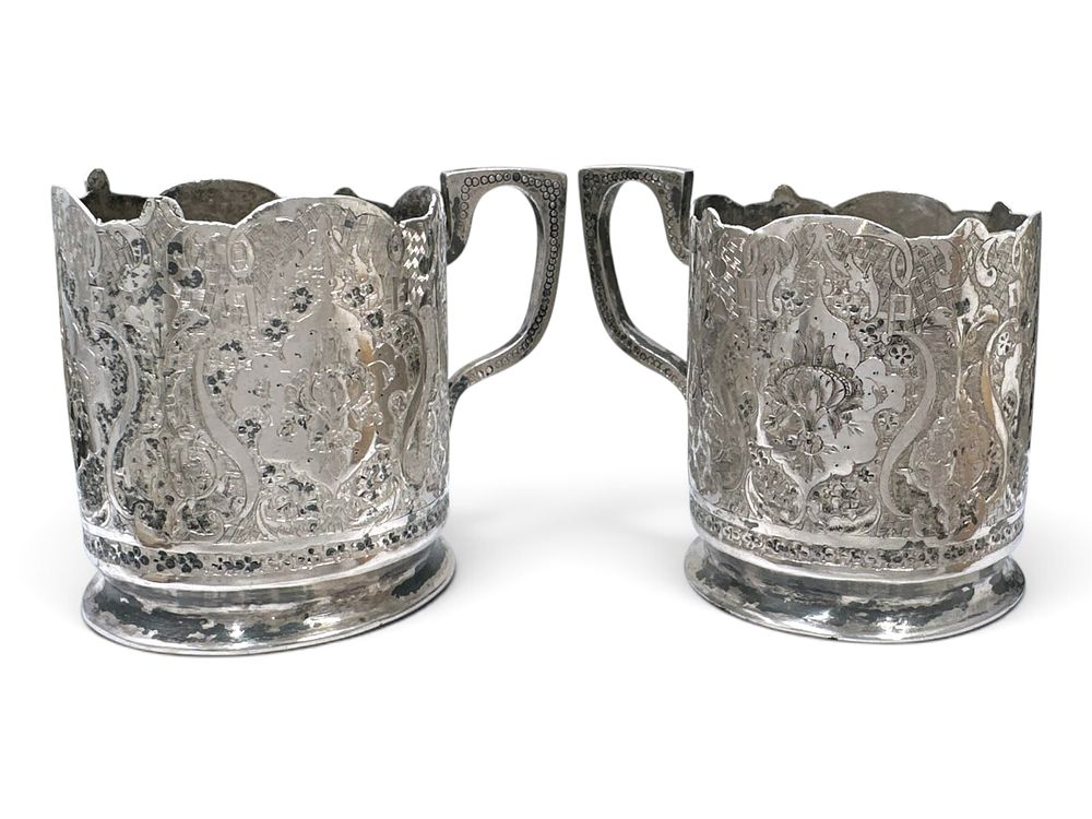 A pair of antique Persian silver (84) tea glass holders with handles, decorated with dense 