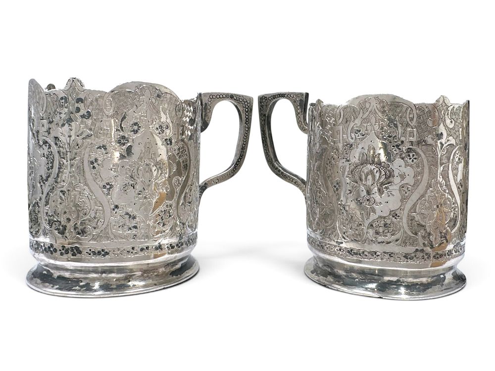 A pair of antique Persian silver (84) tea glass holders with handles, decorated with dense 