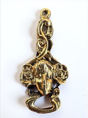תליון ארט נובו עתיק מצופה זהב, מעוטר בתבליט ראש אשה. אורך: 4 ס״מ.