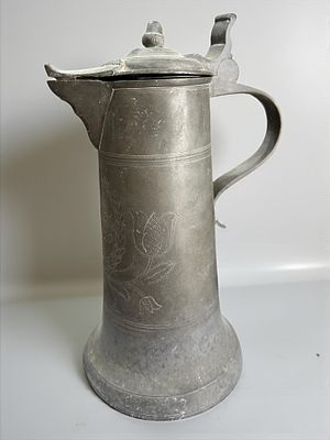 קנקן בירה עתיק מהמאה ה19 עשוי פיוטר מעוטר חריטות. מידות: 15x30 ס"מ.