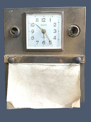 מתקן שולחני הכולל שעון מכני (תקין), לצידין מתקן ל2 עטים ופנקס. שנוןת ה30-40. מידות: 12x14 ס"מ.