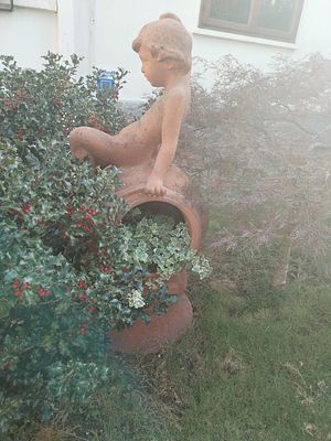 Figura di fanciullo seduto su un'anfora in terracotta cm 150. Incorniciata in un'estetica rurale 