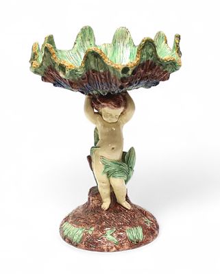 A 19th Century Majolica centrepiece, modelled with shell shaped bowl held aloft by putti figure 