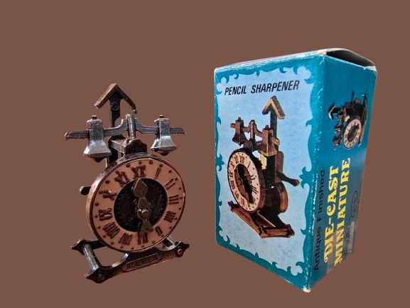 Vintage pencil sharpener made of bronze-tone cast metal - Antique clock in the original packaging. 