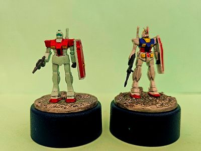 Two pencil sharpeners with hand-drawn robot figures of models from the Japanese "Gundam" series. 