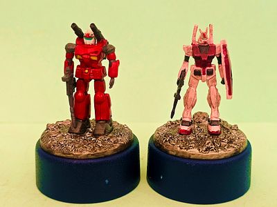 Two pencil sharpeners with hand-drawn robot figures of models from the Japanese "Gundam" series. 