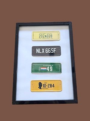 Framed collection of historical international metal miniature car license plates. Rare 