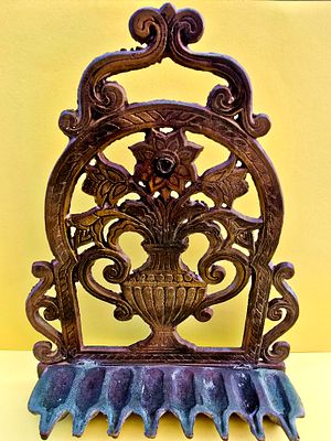 A heavy, antique menorah made of bronze, in a vintage design of a jug with flowers, designed 