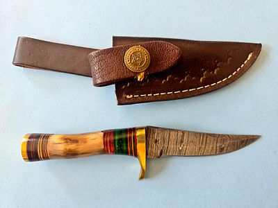 A handmade hunting knife made of Damascus steel, including a deer bone handle and an animal 