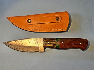 A handmade hunting knife made of Damascus steel, including a combined handle of mahogany and 