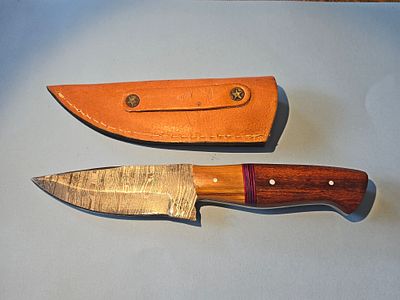 A handmade hunting knife made of Damascus steel, including a combined handle of mahogany and 
