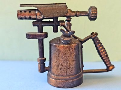 A vintage cast metal pencil sharpener in the shape of a gas burner (Blowtorch), usually 