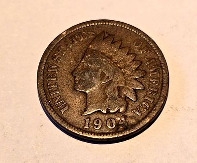 American "Indian Head Cent" coin from 1904. The coin depicts the image of "Liberty" wearing a 