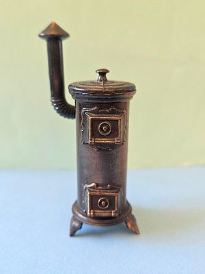 A vintage cast metal pencil sharpener in the shape of a wood stove, often produced by the 
