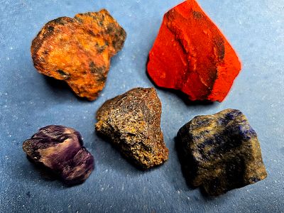 A collection of raw, unprocessed gemstones. The stones are natural, not polished or processed 