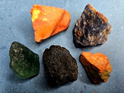 A collection of raw, unprocessed gemstones. The stones are natural, not polished or processed 