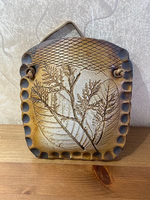 קרמיקה עבודת יד מעוצבת לתלייה מאת האמן יהודה קורן. גודל: 16/15 ס"מ. 
נזק קל בצד האחורי.