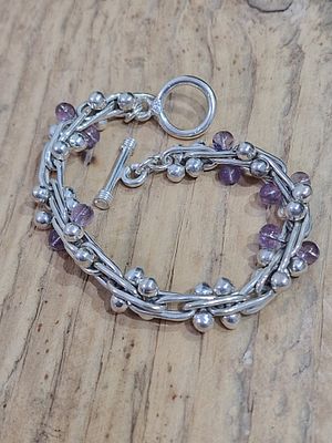 צמיד בסגנון מנוקד הכולל חוליות כסף סטרלינג שזורות וחרוזי אמטיסט קטנים, נסגר באמצעות אבזם T-bar. 