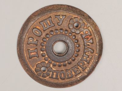 Накладка на звонок "Прошу повернуть". Начало ХХ в. Чугун, литье. Диаметр 6,3 см. 
Следы 