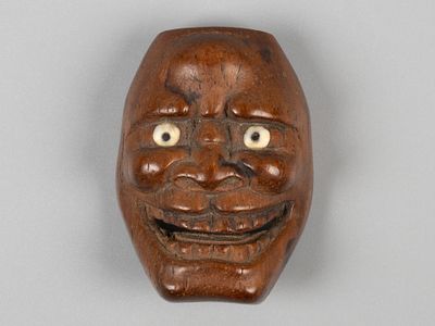 Нэцкэ. Маска театра Но. Хання (?). Япония, XIX в. Дерево, резьба, инкрустация. Размер 3,7х2,7 