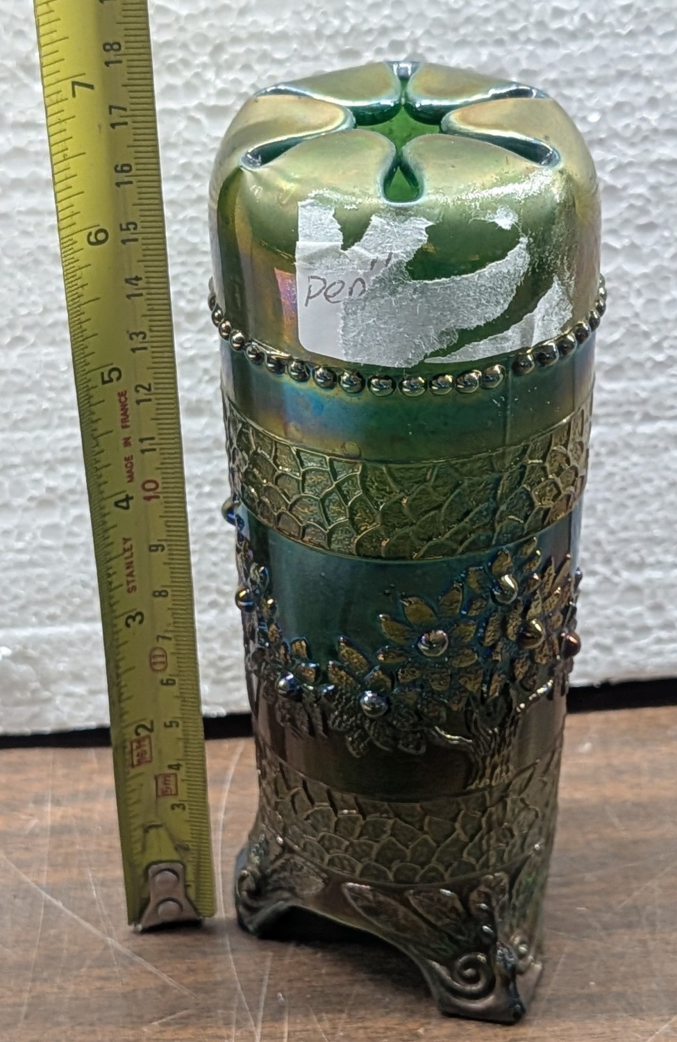 A footed iridescent carnival glass hatpin holder with a tree and blossom pattern