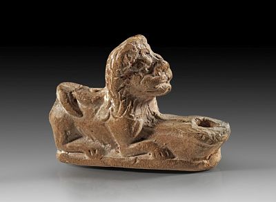 Terracotta lamp of brown clay with redbrown slip depicting a crouching lion. Roman, 1st - 2nd 