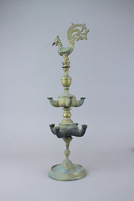 מנוררת שמן הודית עתיקה בעלת שמונה פתילים בשתי קעריות מסודרות בשתי קומות. בראש המנורה פסל של 