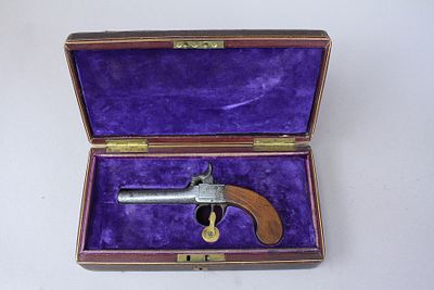 אקדח קטן עם מנעל הקשה (Percusion Lock) כנראה מתוצרת בלגית. קנה קצר ידית עץ מנגנון במצב עבודה 