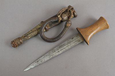 פגיון זרוע (Arm Dagger) , דרום סודן. להב מחושל היטב בחתך מעוין. ידית עץ מקומי. נדן מעוטר בעור 